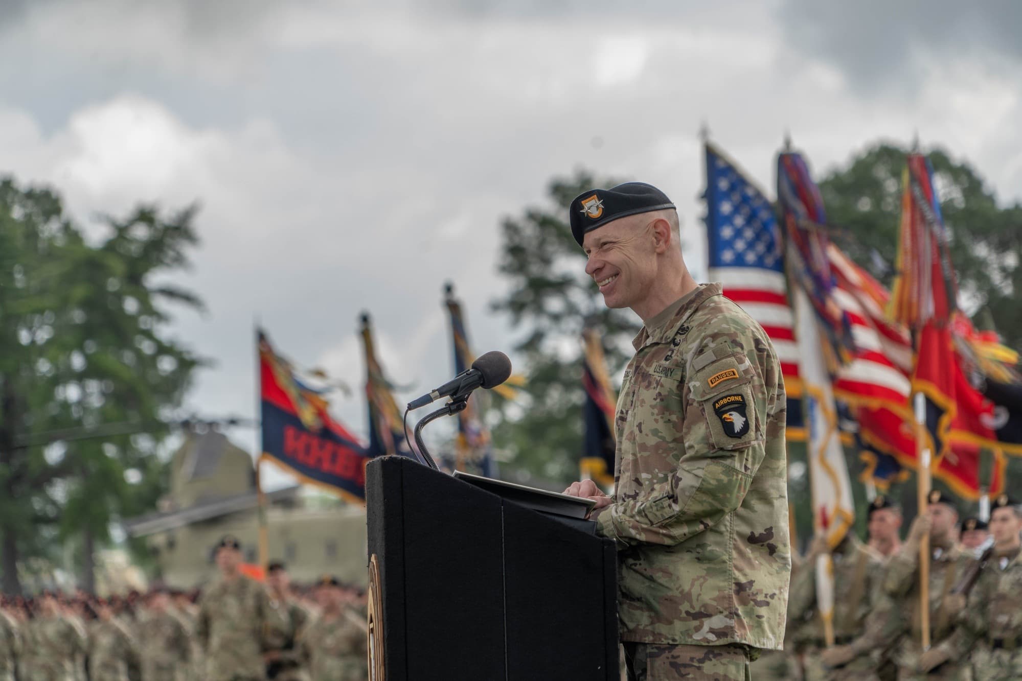 Maj. Gen. Brett Sylvia, in Army uniform and black beret, speaks at a podium during a 101st Airborne Division change-of-command ceremony at Fort Campbell in May 2025.
