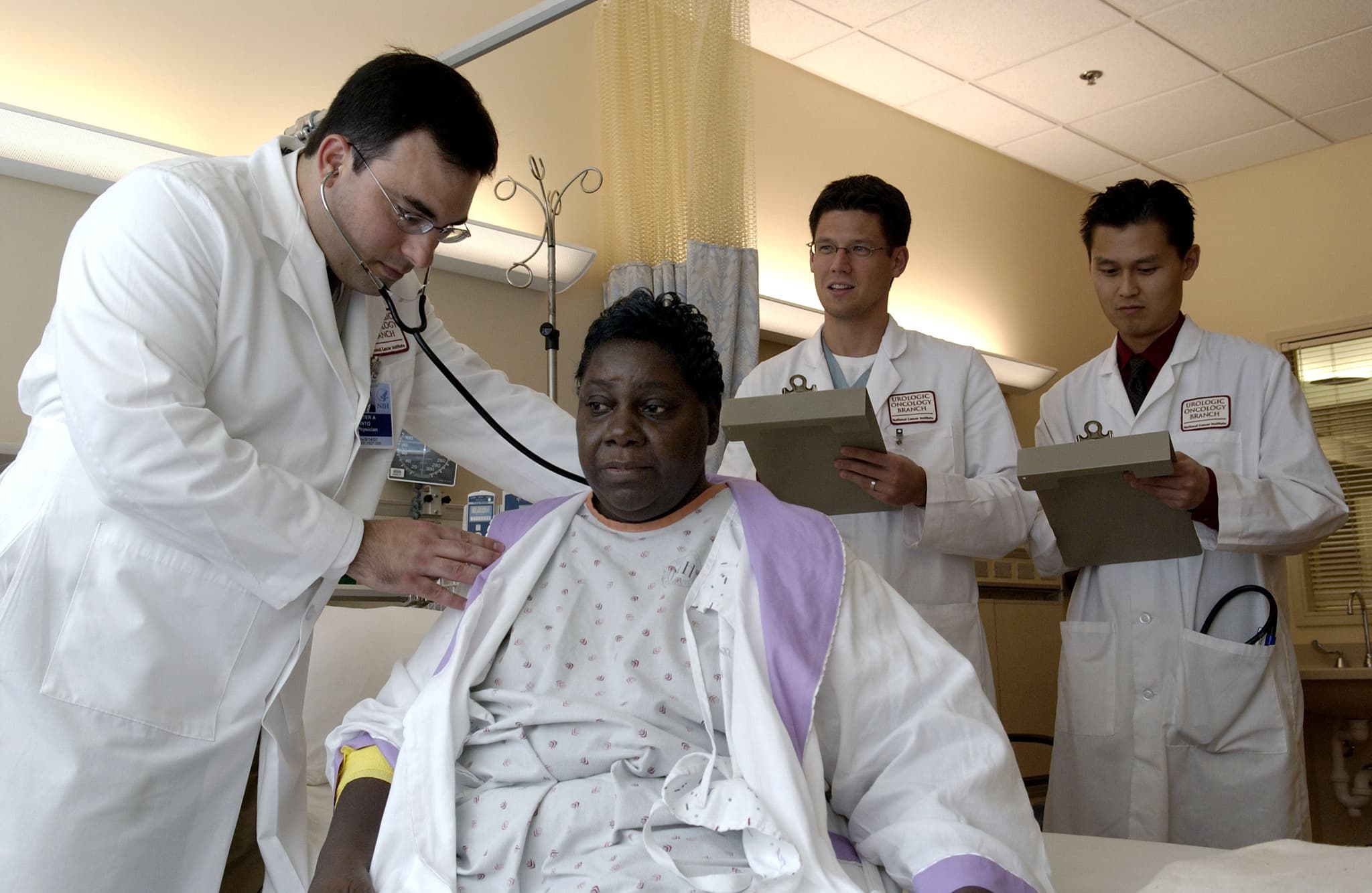 Archive photograph of Dr. Peter Pinto examining a patient with a stethoscope at the National Cancer Institute.